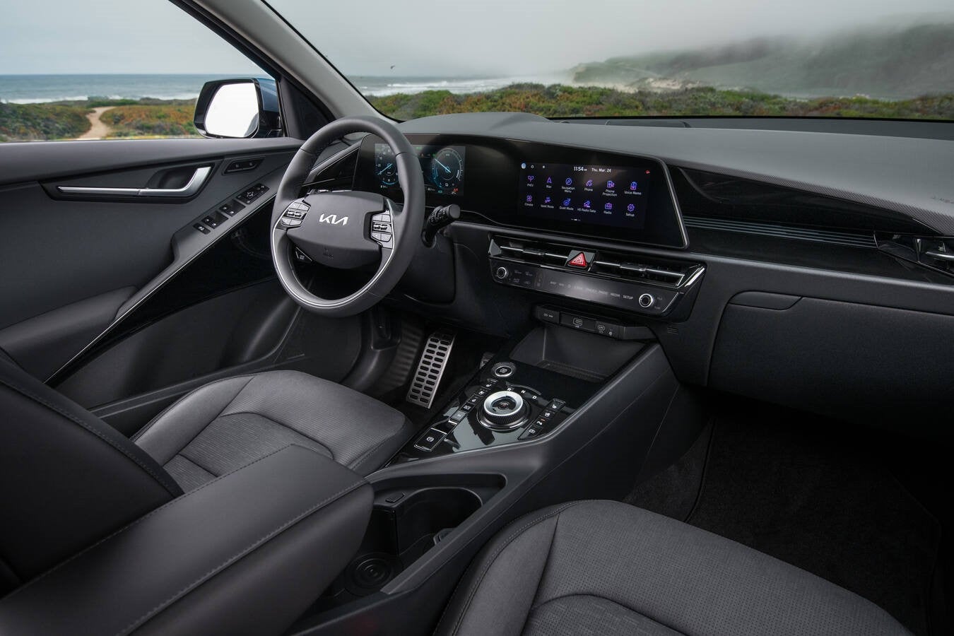 The grey modern interior of the 2026 Kia Niro is seen from the perspective of a person in the front passenger's seat of the Kia subcompact SUV.