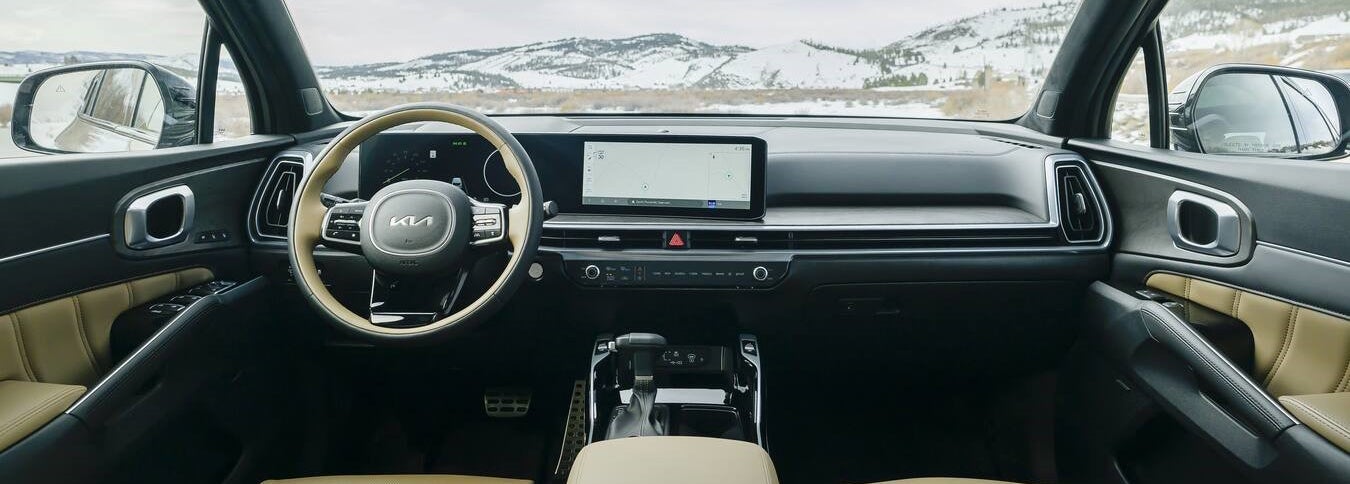 The modern interior of the new Kia Sorento in Phoenix is seen from the back middle seat looking forwards.