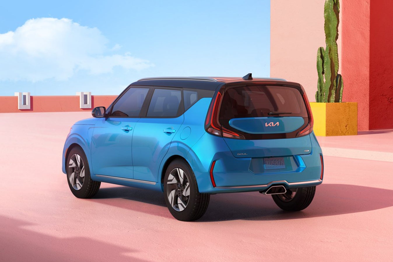 A blue new 2026 Kia Soul in Peoria is parked facing away from the viewer to the left on a bright pink patio on top of a building with a planted cactus in the background.