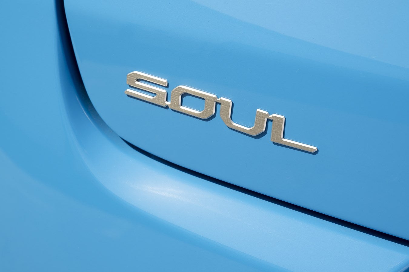 The name "SOUL" is shown up close on the lower left corner of the rear of the blue Kia crossover in Phoenix.