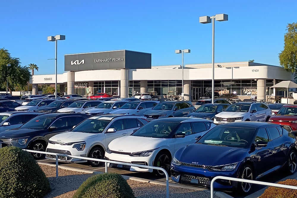 The parking lot and front entrance of Kia Peoria are viewed from a distance.
